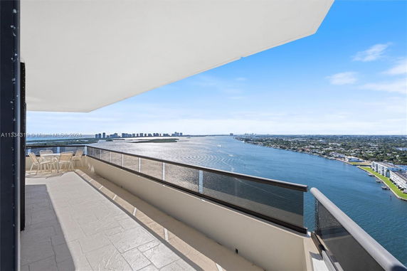 Panoramic view from a high-rise balcony overlooking a large body of water and cityscape.