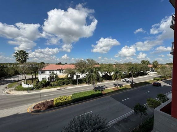 Street view showing a road lined with palm trees and residential buildings.