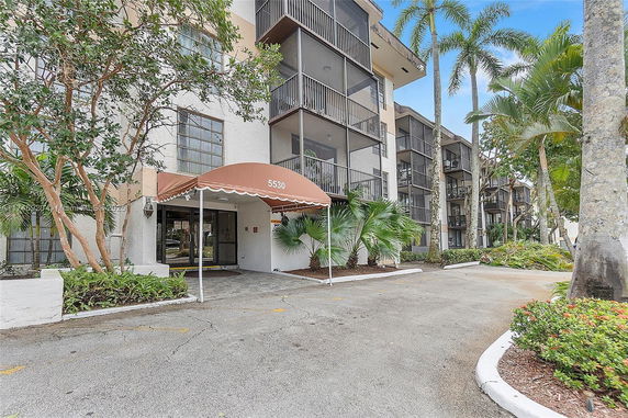 Front view of a multi-story residential building with balconies and an entrance canopy.