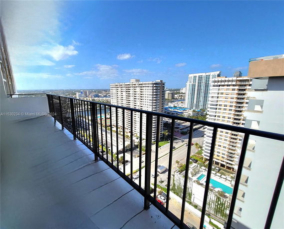 Wide angle view from a high-rise balcony overlooking surrounding buildings and landscape.