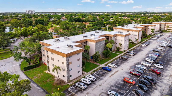 Aerial view of apartment buildings with flat rooftops and parking lot.