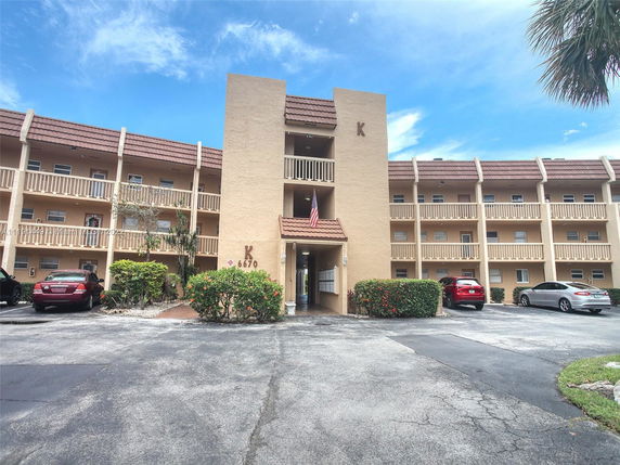 Front view of a multi-story apartment building with parking area.