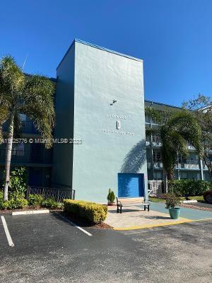 Front view of a multi-story building with a central entrance and surrounding palm trees.