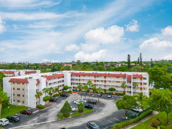 Front view of a multi-story apartment building with a parking area.