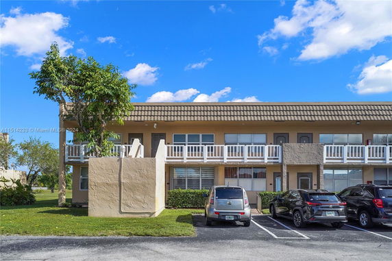 Front view of a two-story residential building with a parking area.
