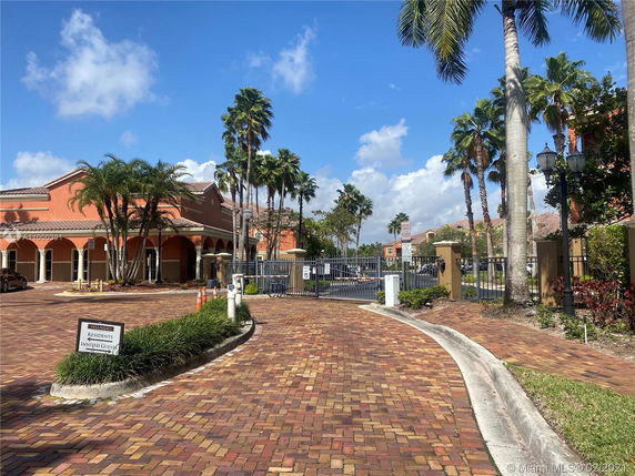 Front view of a building with arched entrances and a paved driveway.
