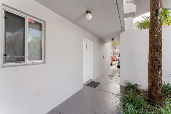 Entryway of a building with a view of parked cars nearby.