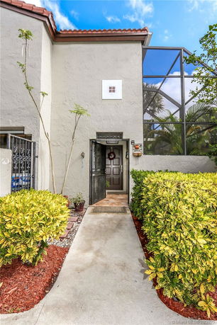 Front view of a house with an open entrance door and garden path.