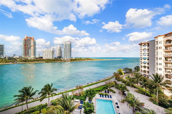 View of waterfront buildings with a pool and palm trees in the foreground.