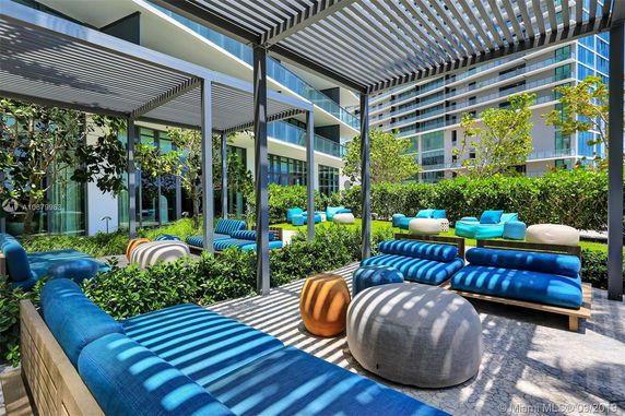 Outdoor seating area with modern furniture adjacent to a multi-story building.