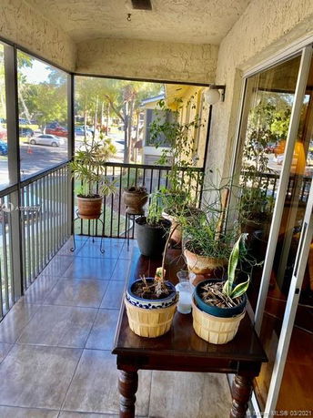 View from a balcony with potted plants overlooking a street.