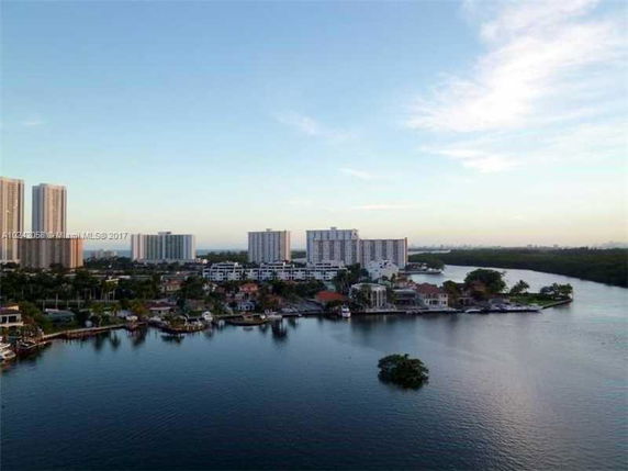 Panoramic view of waterfront buildings with a river or bay in the foreground, featuring several mid-rise and high-rise structures.