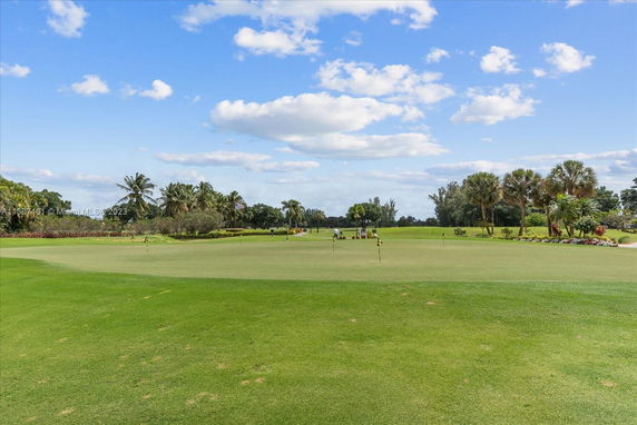 Wide view of a golf course with lush greenery and palm trees.
