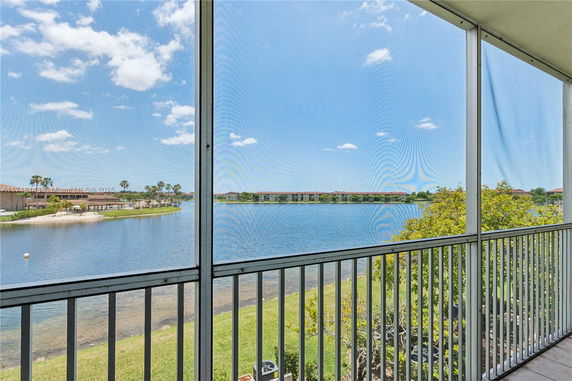 View of a lake and surrounding area from a screened balcony.