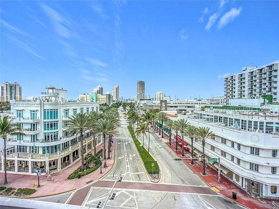 Aerial view of a city street with mid-rise buildings and palm trees.