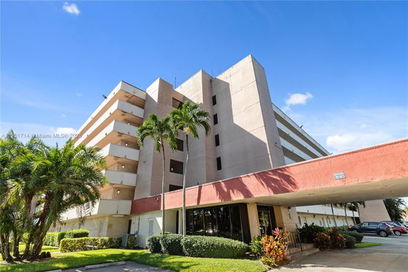 Front view of a multi-story residential building with balconies and a covered entrance.