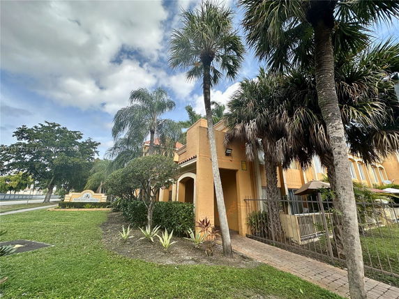 Front view of a building with archways and palm trees.