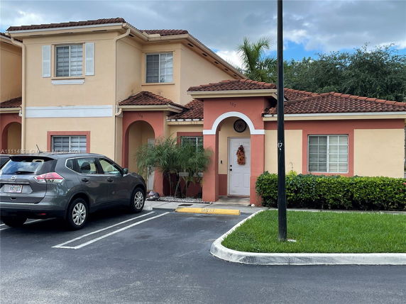 Front view of a two-story house with an arched entrance and tiled roof.
