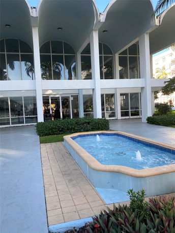 Front view of a modern two-story building with large glass windows and a decorative fountain in front.