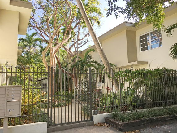 Front view of a two-story building with metal fencing and greenery.