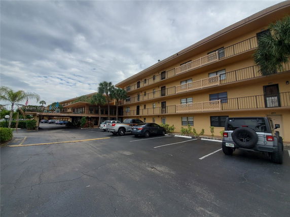 Front view of a multi-story building with parking spaces in front.