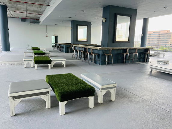 Rooftop area with benches and a bar featuring stools and mirrors.