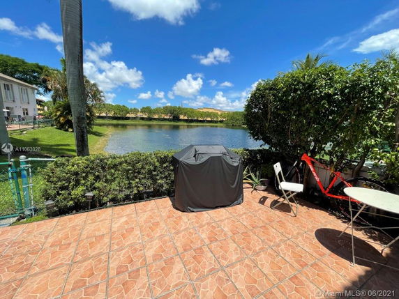 Patio overlooking a lake with a barbecue grill and outdoor seating area.