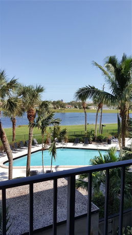 View from a balcony overlooking a swimming pool and a lake in the background.
