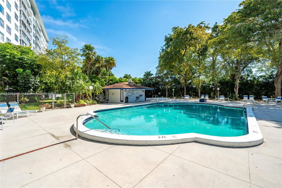 Outdoor swimming pool area with surrounding trees and poolside seating.