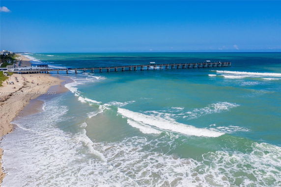 Aerial view of a beach with a long pier extending into the ocean.