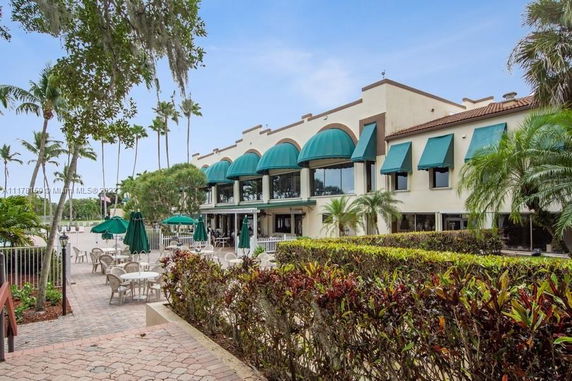 Front view of a building with green awnings and an outdoor seating area.