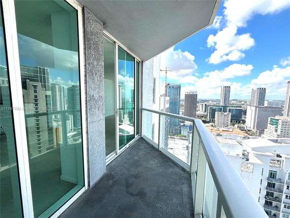 Balcony view overlooking a cityscape with tall buildings and a blue sky.