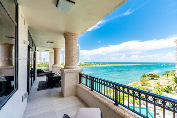 Balcony view overlooking the ocean with nearby high-rise buildings.