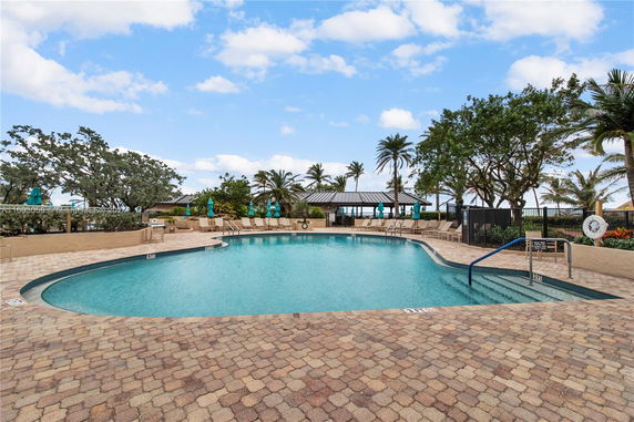 Outdoor swimming pool area with lounge chairs and umbrellas.