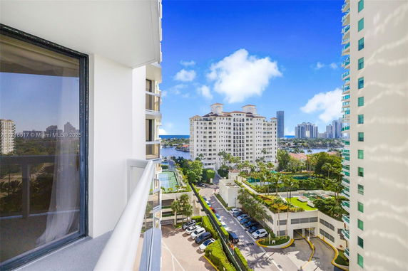 View from a balcony showing multiple high-rise buildings and a parking area.
