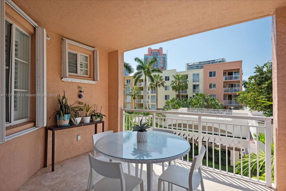 Balcony view overlooking nearby residential buildings with tropical plants in the foreground.