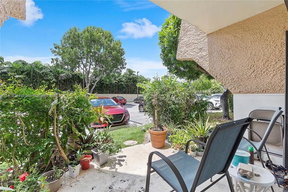 Outdoor parking area with parked cars and surrounding greenery.