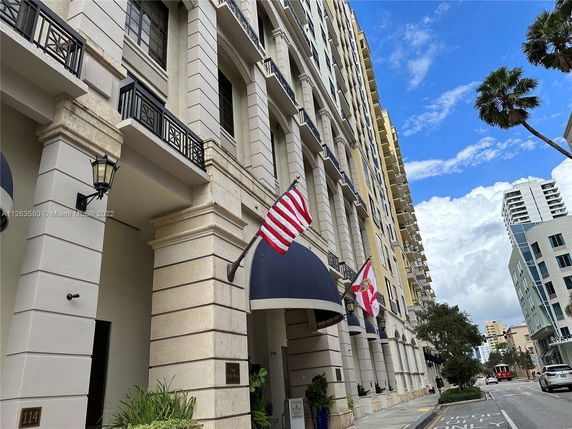 Front view of a multi-story building with flags and decorative columns.