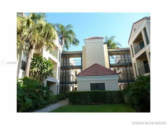 Front view of a multi-story building with balconies and tiled roofs.