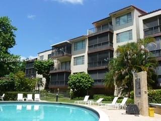 Multi-story residential building with balconies and a swimming pool in the foreground.