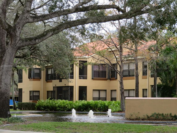 Front view of a two-story building with large windows and a fountain in the foreground.