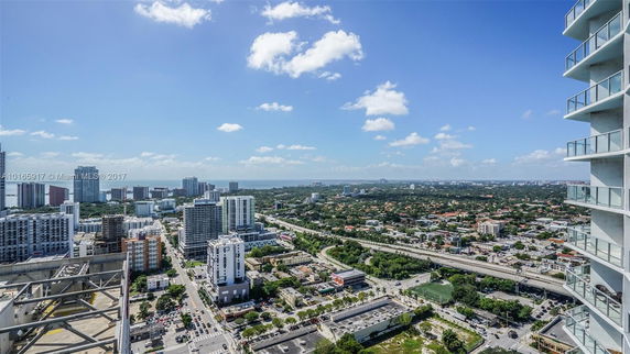Wide angle view of a cityscape with multiple high-rise buildings, roads, and distant green areas.