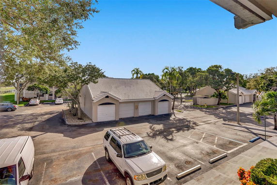 Outdoor parking area with vehicles and a building with multiple garage doors.