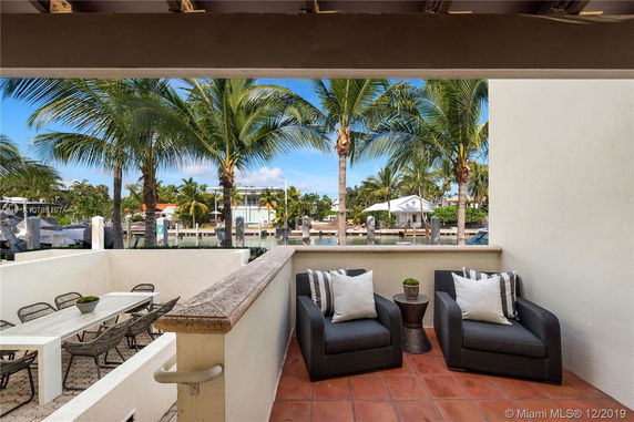 View from residential outdoor seating area showing palm trees and nearby buildings.