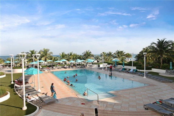 Outdoor swimming pool area with lounge chairs and umbrellas.