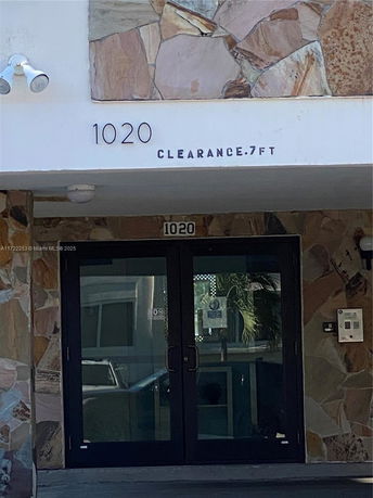 Front view of a building entrance with stone facade and glass doors.