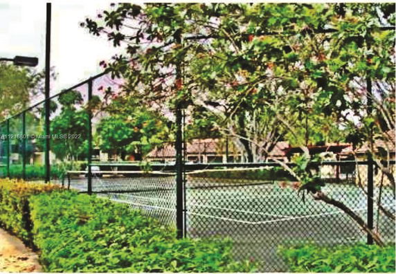 Tennis court surrounded by fence and trees