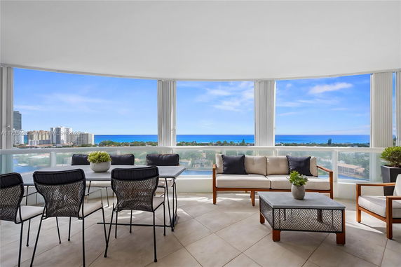 Balcony view overlooking cityscape and ocean with outdoor seating area.