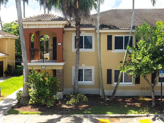 Front view of a two-story house with a tiled roof and a small balcony.