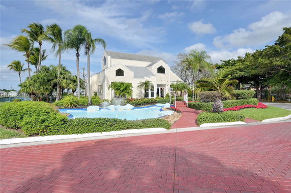 Front view of a two-story house with gable roof and surrounding garden.